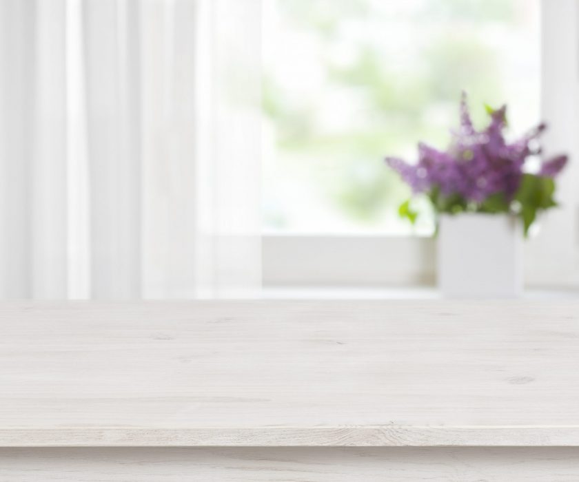 Wooden table on defocused window with purple flower pot background Wooden table on defocused window with purple flower pot background